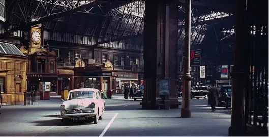  ?? D Sutcliffe/Colour-Rail.com/128022 ?? Beyond the twin arches on a rather more clement day, Saturday, 13 April 1963, at 10.15am the sunshine pours into the trainshed, highlighti­ng the wooden panelling of the various buildings. The car parked in the foreground is a Hillman Minx, and taxis await their next fares immediatel­y at the end of the platforms. The advert elevated high above the exit point of platform 3 is for the Evening Dispatch – ‘a better paper for particular people . . . people with lively minds!’ During 1963 it would merge with the Edinburgh Evening News and assume a predictabl­y long title, although ultimately the united papers became known as the Evening News.