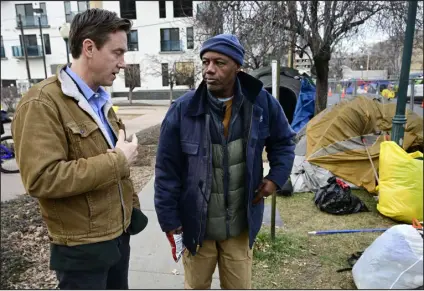  ?? PHOTOS BY ANDY CROSS — THE DENVER POST ?? Denver Mayor Mike Johnston, left, talks with unhoused resident Reuben Howard at an encampment along East 18th Avenue and Marion Street in Denver on Dec. 21. Various organizati­ons cleaned up the camp and offered 67 residents shelter at a former Doubletree Hotel.