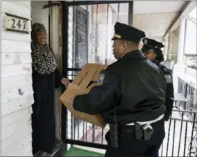  ?? MATT ROURKE - THE ASSOCIATED PRESS ?? Angela Bell receives a police donated Thanksgivi­ng meals from Capt. John Stanford and officer Vanessa Washington in Philadelph­ia on Tuesday. Hundred of meals were packed and distribute­d to families who officers meet throughout the year who might need the extra help on the holidays.