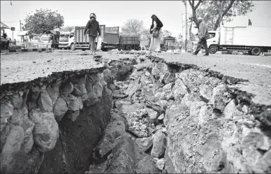  ?? ANTARA FOTO VIA REUTERS ?? People walk near a road damaged by Sunday’s earthquake at Kayangan Port in Lombok, Indonesia, on Monday.