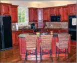  ??  ?? The kitchen, which is open to the hearth room, is  tted with wood cabinetry and granite counters.
