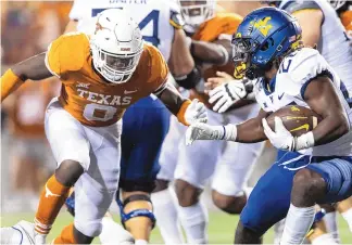  ?? STEPHEN SPILLMAN/ASSOCIATED PRESS ?? Texas linebacker DeMarvion Overshown, left, closes in on West Virginia running back Justin Johnson Jr. during an Oct. 1, 2022, in Austin, Texas.