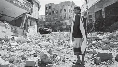  ??  ?? A man walks past a damaged building in Aden, Yemen, where some of the prisons are said to be based. (Photo: National Yemen)