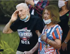  ?? JOEL ROSENBAUM — THE REPORTER ?? With his girlfriend, Jean Eldridge (right) at his side, Gerald Simoni, 103 of Vacaville salutes as an American flag is raised by members of the 60th Medical Wing from Travis Air Force Base in front of his residence at Cogir of Vacaville Senior Living Tuesday to celebrate his birthday.