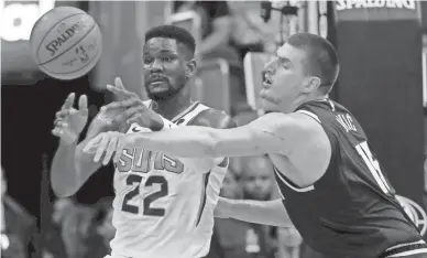  ??  ?? Suns center Deandre Ayton (22) passes as Nuggets center Nikola Jokic defends during the first half of a preseason game on Monday night in Phoenix. AP