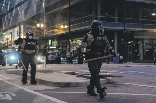  ?? TYLER LARIVIERE/SUN-TIMES ?? Members of Illinois State Police walk near the Thompson Center in the Loop during unrest on May 30, 2020.