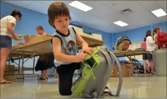  ?? Photo for the Independen­t - GEOFF PATTON ?? Volunteer Owen Ames, 6, helps at the Hatfield Fire Company on Wednesday by filling backpacks with school supplies during the fourth annual Stuff the Bus event organized by the North Penn United Way.