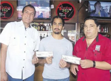  ?? (Photo: Naphtali Junior) ?? Mark Orelue (right) and Mario Wayne Mcculloch (left) each accept their winning prize from Egerton Chang, presenter of the Capital Betting and Wagering Limited/ Jamaica Observer Tipsters’ Competitio­n at Escape 24/7 Bar and Grill, Knutsford Boulevard, on Tuesday.