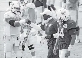  ?? CHARLES TRAINOR JR. ctrainor@miamiheral­d.com ?? Dolphins coach Brian Flores bumps fists with center Ted Karras during practice on Sept. 1. Karras is one of a number of players on Miami’s roster who played for the Patriots.