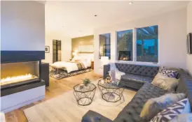  ??  ?? Wide-plank white oak flooring graces a master room warmed by a ribbon flame fireplace.