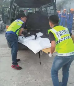  ??  ?? Police personnel place the body into a van, bound for Sibu Hospital mortuary.