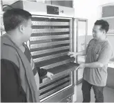  ??  ?? NEWLY INSTALLED - Dr. Renerio S. Mucas (right) who headed the research team poses with Roderick Cañuto of Ephrathah Farm with the newly installed programmab­le electronic dehydrator. It has 12 layers of food grade stainless steel that can dry leaves of malunggay, guyabano, and guava in eight hours.