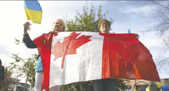  ?? JIM WELLS ?? Tetiana Kyrychenko left, who came to Canada from Ukraine in 2014, and Marina Shugaeva, who came to Canada from Russia in 2003, join members of Calgary's Ukrainian community gathered at 10th Street and Memorial Drive N.W. in Calgary on Sunday to thank Canada for supporting Ukraine in its time of war.