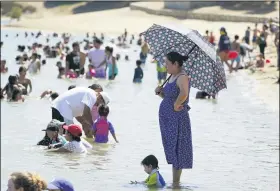  ?? MARCIO JOSE SANCHEZ — THE ASSOCIATED PRESS ?? A visitor shields herself from the sun with an umbrella in a swimming beach Sept. 5 at Castaic Lake in Castaic.