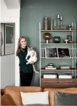  ??  ?? Living room Tan leather, warm woods and splashes of white bring the dark grey-green walls to life. The sofas are both from Ikea but Cajsa (right) has customised them with new legs from Pretty Pegs. The slanted shelves on the ‘String’ wire storage...