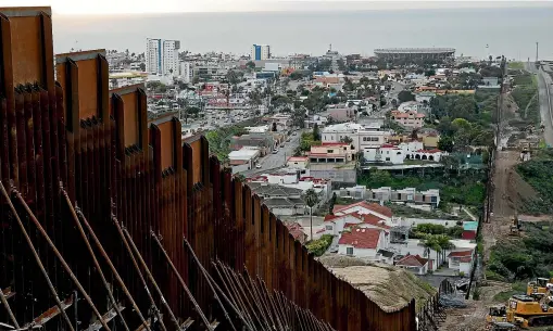  ?? AP ?? A section of newly-replaced border wall separates Tijuana, Mexico, above left, from San Diego, right, in San Diego. Border Patrol officials say some Mexican homes and structures encroach on US soil, posing a dilemma for authoritie­s when replacing the wall.