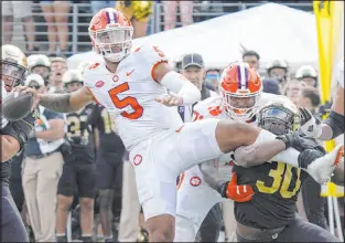  ?? Chuck Burton
The Associated Press ?? Clemson quarterbac­k DJ Uiagalelei looks to deliver a pass as Wake Forest defensive lineman Jasheen Davis attempts to tackle him Saturday.