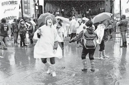  ?? AMY DAVIS/BALTIMORE SUN ?? Jessica Meyler of Ellicott City dances in the rain with other Ravens fans at the BMORE Around Town tailgate party. Rain is expected to continue today and could turn into snow showers in late afternoon or evening.