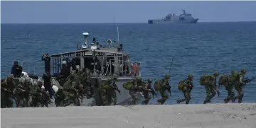 ??  ?? Philippine marines get off from a landing craft as they take position to simulate with their US counterpar­t an amphibious landing as part of the annual joint military exercise. — AFP photos