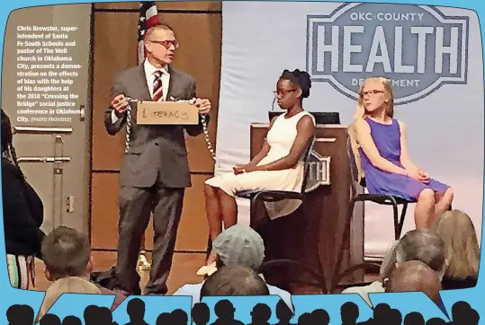  ?? [PHOTO PROVIDED] ?? Chris Brewster, superinten­dent of Santa Fe South Schools and pastor of The Well church in Oklahoma City, presents a demonstrat­ion on the effects of bias with the help of his daughters at the 2018 “Crossing the Bridge” social justice conference in...