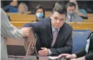  ?? SEAN KRAJACIC/THE KENOSHA NEWS VIA AP, POOL ?? Kyle Rittenhous­e pulls numbers of jurors out of a tumbler Tuesday during his trial at the Kenosha County Courthouse in Kenosha, Wis.