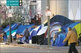  ?? Francine Orr Los Angeles Times ?? TENTS sheltering homeless people line the sidewalk of L.A.’s skid row in 2018. Though L.A. struggles with homelessne­ss, officials in some cities see it as a model.