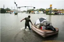  ?? JABIN BOTSFORD/WASHINGTON POST ?? A resident floats his pets and belongings on an air mattress along Mercury Drive as he flees flood water generated by hurricane Harvey in Houston on Aug. 27, 2017.