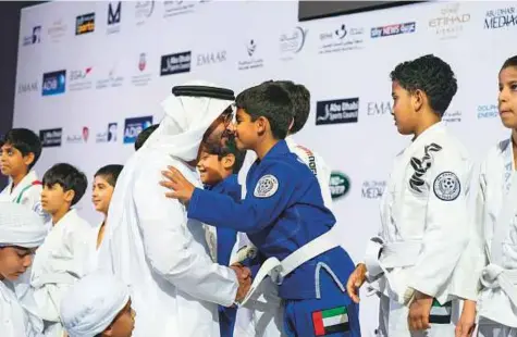  ??  ?? Shaikh Mohammad greets a young participan­t during the Abu Dhabi Jiu-Jitsu Festival at Mubadal Arena in Zayed Sports City yesterday. WAM