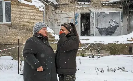  ?? ?? Defiant amid adversity: reznychenk­o (right) crying as she speaks with her neighbour near a work of banksy at the wall of destroyed building in the Ukrainian village of Horenka, which was heavily damaged by fighting in the early days of the russian invasion. — reuters