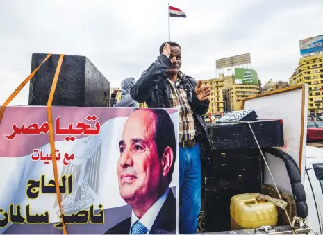  ?? (AFP) ?? A supporter of Egyptian President Abdel Fattah al Sisi stands on a pickup truck adorned with a poster bearing Sisi’s portrait, in Cairo’s Tahrir Square on January 25