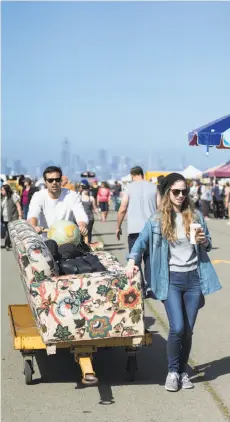  ??  ?? Above: Jessica Dinitz, right, and Adrian Abundes wheel a couch they purchased at the Alameda Point Antiques Faire. The couple bought the couch to decorate their wedding venue. Below: Vintage Easter decoration­s are displayed for sale.