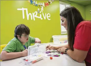  ?? JASON GETZ/JASON.GETZ@AJC.COM ?? Noah Cole (left) works with volunteer Kayla Cox on artwork in the Thrive Special Needs Ministry at First Baptist Church Woodstock. The ministry works with people of all ages.