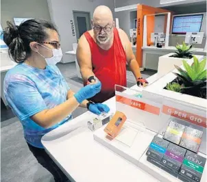  ?? JOE BURBANK/ORLANDO SENTINEL ?? Sales rep Jenalee Medina, left, shows a vaping device to a customer on June 12 at the MUV Dispensary, a medical marijuana store in downtown Orlando.