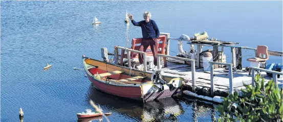  ?? Kathy Johnson ?? Floyd Stewart waves from his small wharf at Lockeport’s Little Big Harbour where his flotilla of more than 30 miniature vessels are displayed during the summer season.