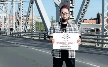  ?? LAURA BARTON/POSTMEDIA NEWS ?? Lucas Spinosa, chairman of Feast Street Niagara, holds a sign about the event happening this weekend in downtown Welland. It will feature 35 food vendors on East Main Street, shutting part of it down, but access to the bridge, on which he stands in...