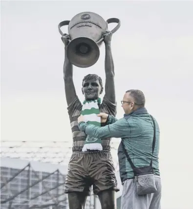  ??  ?? 0 Celtic fan Gerry Campbell places a scarf on the statue of Billy Mcneill outside Celtic Park, where tributes from the club honoured the man universall­y known as Cesar