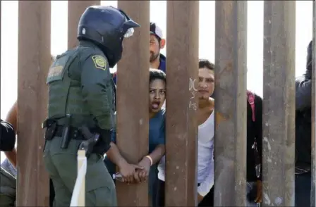  ?? GREGORY BULL — THE ASSOCIATED PRESS ?? Migrants from Central America yell through a border wall at a U.S. Border Patrol agent after he pulled down a banner Sunday in San Diego.