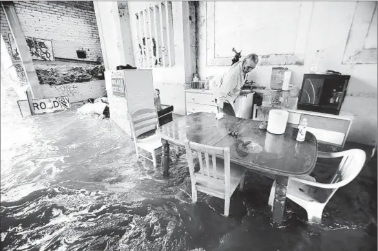  ?? Genaro Molina Los Angeles Times ?? FELIPE FLORES LOPEZ’S belongings ride currents as he helplessly watches his encampment under a bridge in Lincoln Heights get destroyed by El Niño f looding.