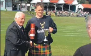  ??  ?? Murdo Masterson accepts his prize at Braemar Gathering after lifting the Glenfiddic­h U-25 heavy events championsh­ip.