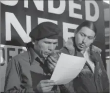  ?? JIM MONE — THE ASSOCIATED PRESS FILE ?? In this file photo taken in Wounded Knee, S.D., American Indian Movement leader Dennis Banks, left, reads an offer by the U.S. government seeking to effect an end to the Native American takeover of Wounded Knee. Looking on is AIM leader Carter Camp....