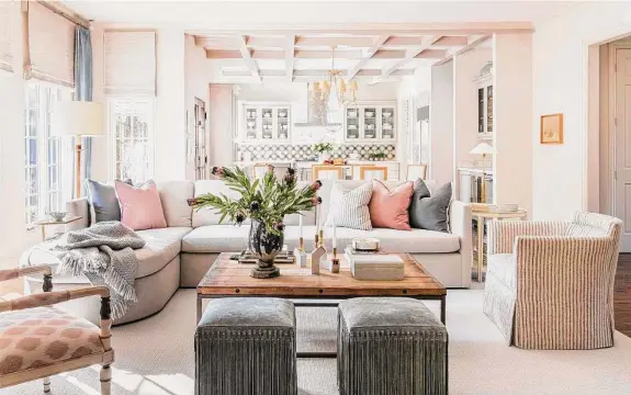  ?? Photos by Julie Soefer ?? Sassy fringed ottomans add whimsy to the family room, while a sectional sofa with a rounded chaise adds softness to the otherwise square room.