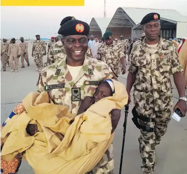  ?? HAMZA SULEIMAN/THE ASSOCIATED PRESS ?? Nigerian army Maj.-Gen. Rogers Nicholas carries a schoolgirl, one of 91 who were freed by Boko Haram extremists, during a handover in Maiduguri, Nigeria, on Wednesday. An estimated 110 girls were kidnapped last month.