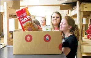  ??  ?? ANGELA SPENCER/ THREE RIVERS EDITION Megan Fernau, right, and Jordan Shook help pack boxes of food at the Beebe Food Pantry as a project for one of their classes.