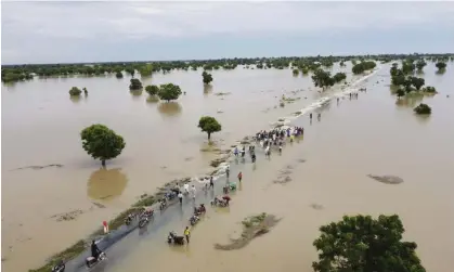  ?? ?? People walk through floodwater­s after heavy rainfall in Hadeja, Nigeria. Photograph: AP Photo/AP