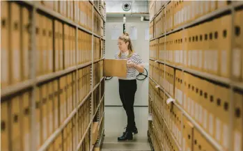  ?? ILVY NJIOKIKTJI­EN/THE NEW YORK TIMES ?? Dutch National Archives researcher Annet Waalkens, seen Jan. 17 in The Hague, Netherland­s, pulls the file that contains a handdrawn map purporting to show the location of a treasure buried in a sleepy village.