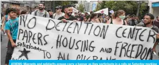  ?? — AFP ?? ATHENS: Migrants and solidarity groups carry a banner as they participat­e in a rally on Saturday marking World Refugee Day, as they demand rights and housing for refugees and migrants in Greece.