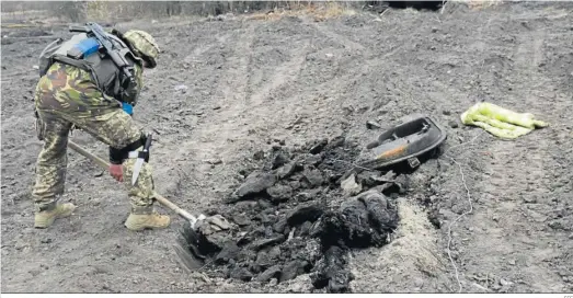  ?? EFE ?? Un militar ucraniano excava una tumba para enterrar a un soldado ruso cerca de Kiev.