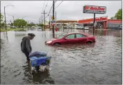  ?? CHRIS GRANGER — THE ASSOCIATED PRESS ?? People carry their belongings down a flooded Broad Street in New Orleans, during a severe rainstorm on Wednesday.