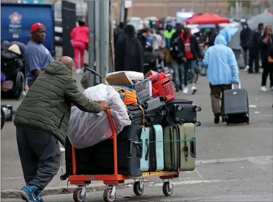  ?? MATT STONE — BOSTON HERALD ?? A man pushes luggage down Atkinson Street. Now officials say a child was taken off the Mile.