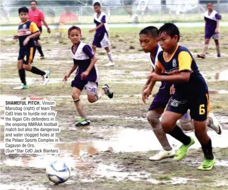  ?? (Sun*Star CdO Jack Biantan) ?? SHAMEFUL PITCH. Vinson Manubag (right) of team CdO tries to hurdle not only the Iligan City defenders in the ongoing NMRAA football match but also the dangerous and water clogged holes at the Pelaez Sports Complex in Cagayan de Oro.